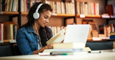 college student listening to music while studying in the library