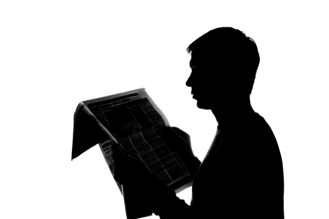 College student thoughtfully reading a newspaper - silhouett