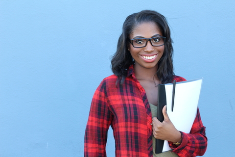 African american female college freshman holding books with a blue background