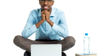 Happy African american college student with laptop, books and bottle of water sitting on white background