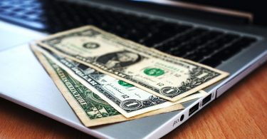 dollar bills sitting on laptop computer on a desk