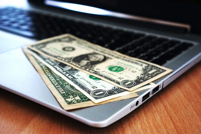 dollar bills sitting on laptop computer on a desk