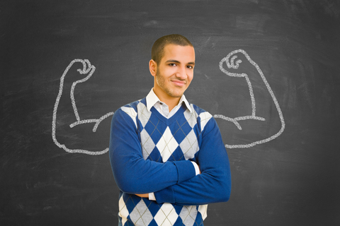 college student in blue sweater standning in front of chalk board with flexing muscles drawn on it