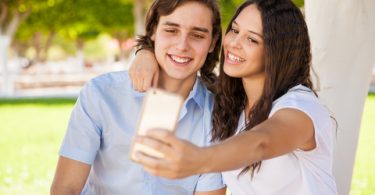 Cute couple of college students taking a selfie at school with a phone