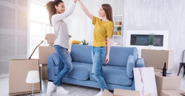 tweo female college roommates doing high five in their new home