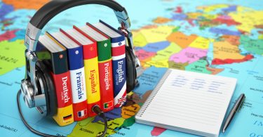 headphones wrapped around textbooks, sitting on a colorful map
