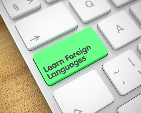 Learn Foreign Languages on Slim Aluminum Keyboard lying on the Wood Background.