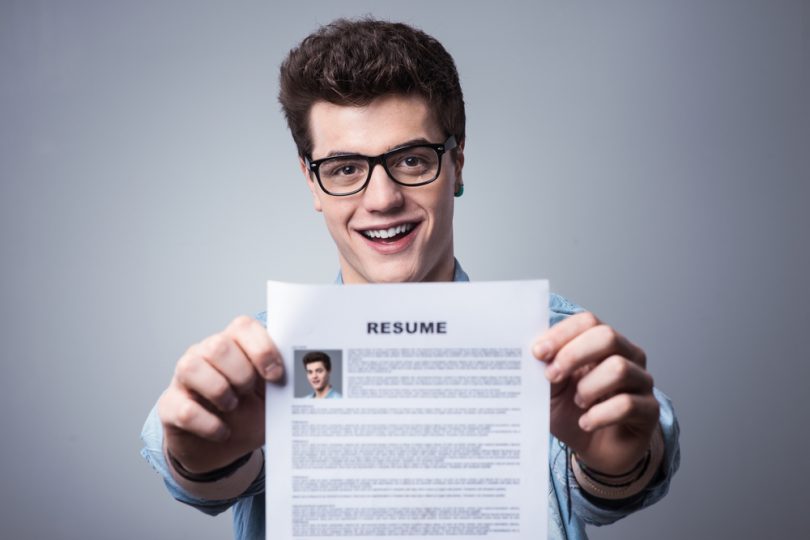 Male college student holding up a resume