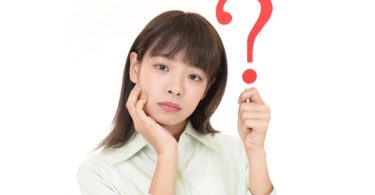 female Asian college student holding up a question mark symbol on white background