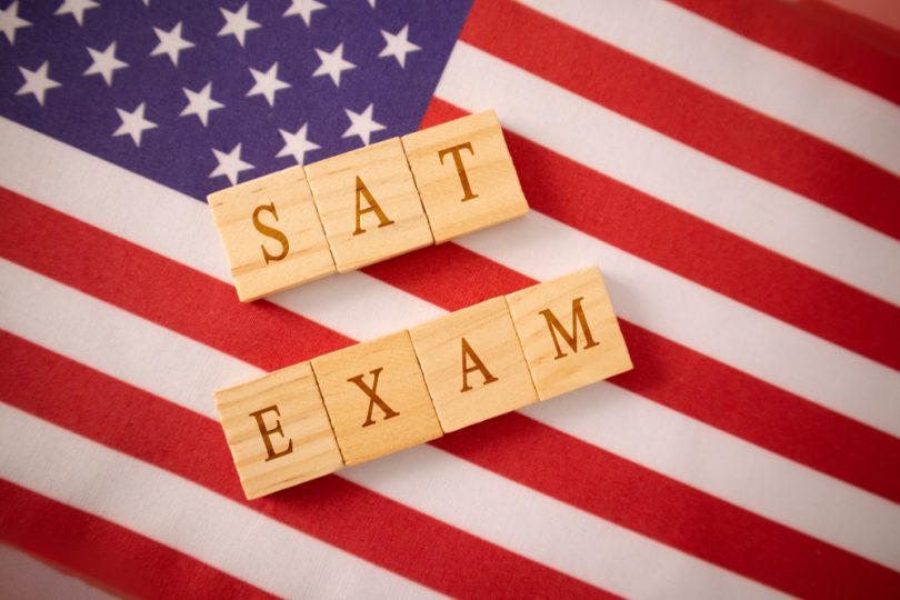 Wooden tiles that spell SAT EXAM on american flag