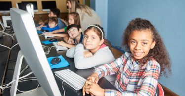 Group of kids learn computer science in a computer class of elementary school