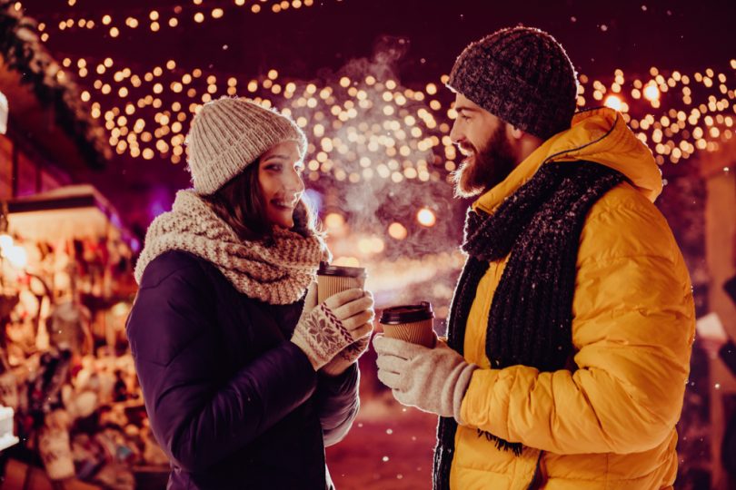 couple on date outside in the winter holding hot drinks