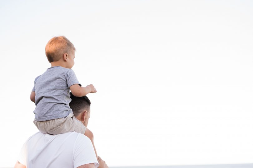 dad holding son on shoulders looking at the sky
